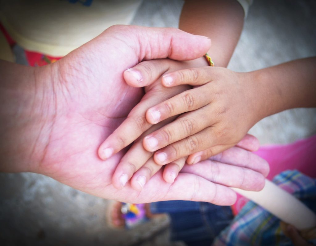 Adult hand holding kids' hands