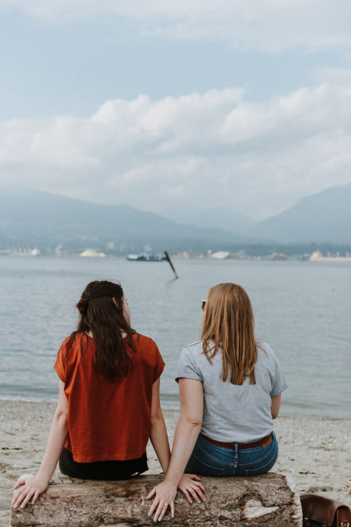 Two women chatting on the sea beach about postpartum challenges