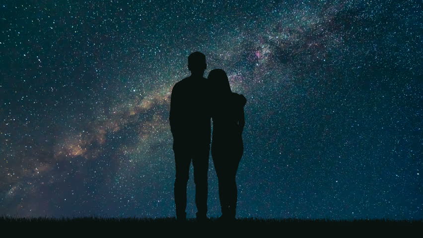 Couple standing and looking at night sky